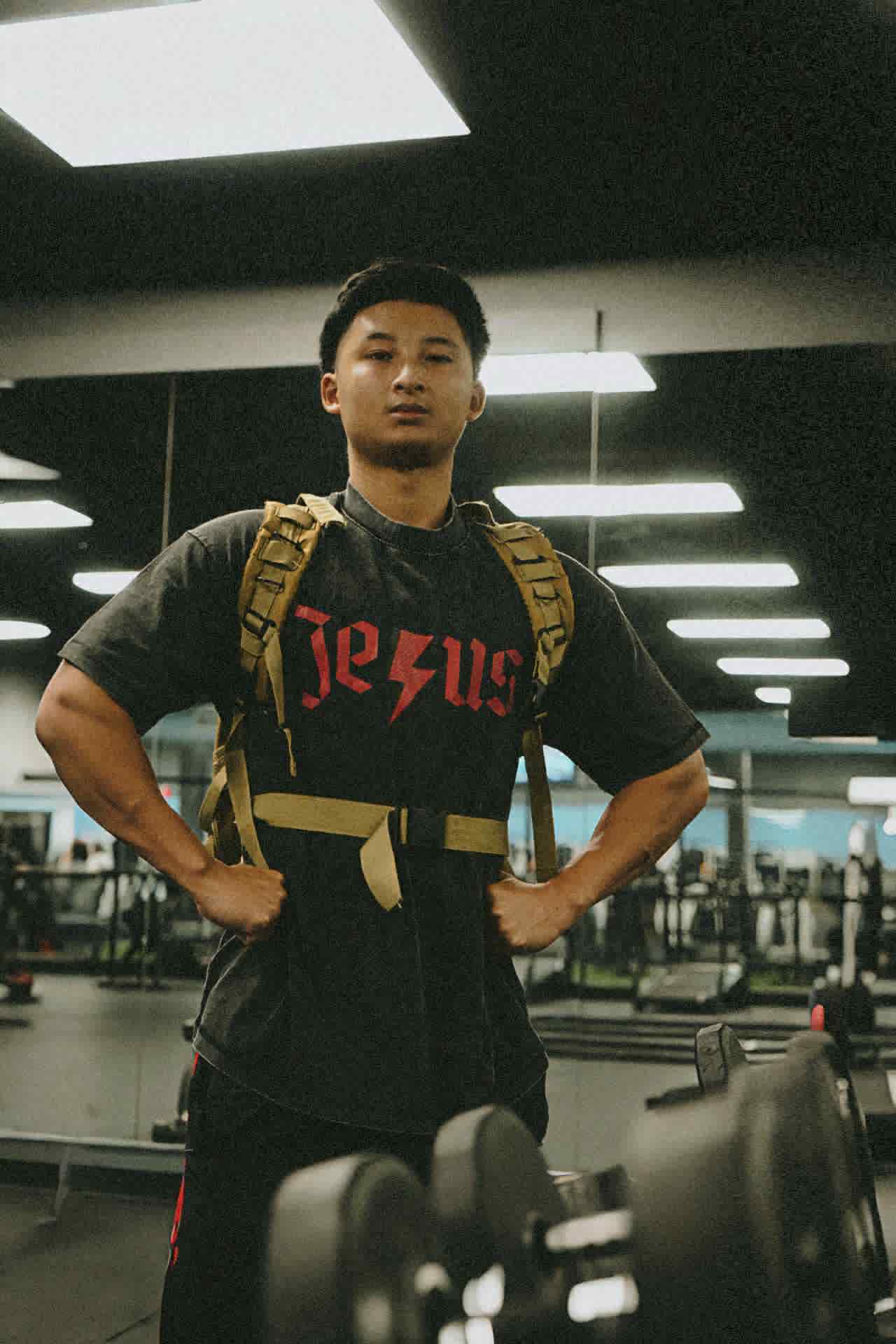 Black t-shirt with 'Jesus' printed on it in a gym.