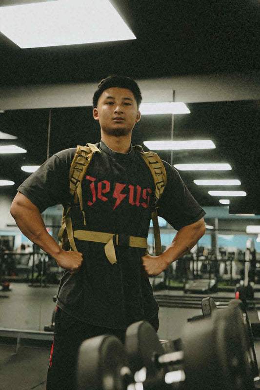 Black t-shirt with 'Jesus' printed on it in a gym.